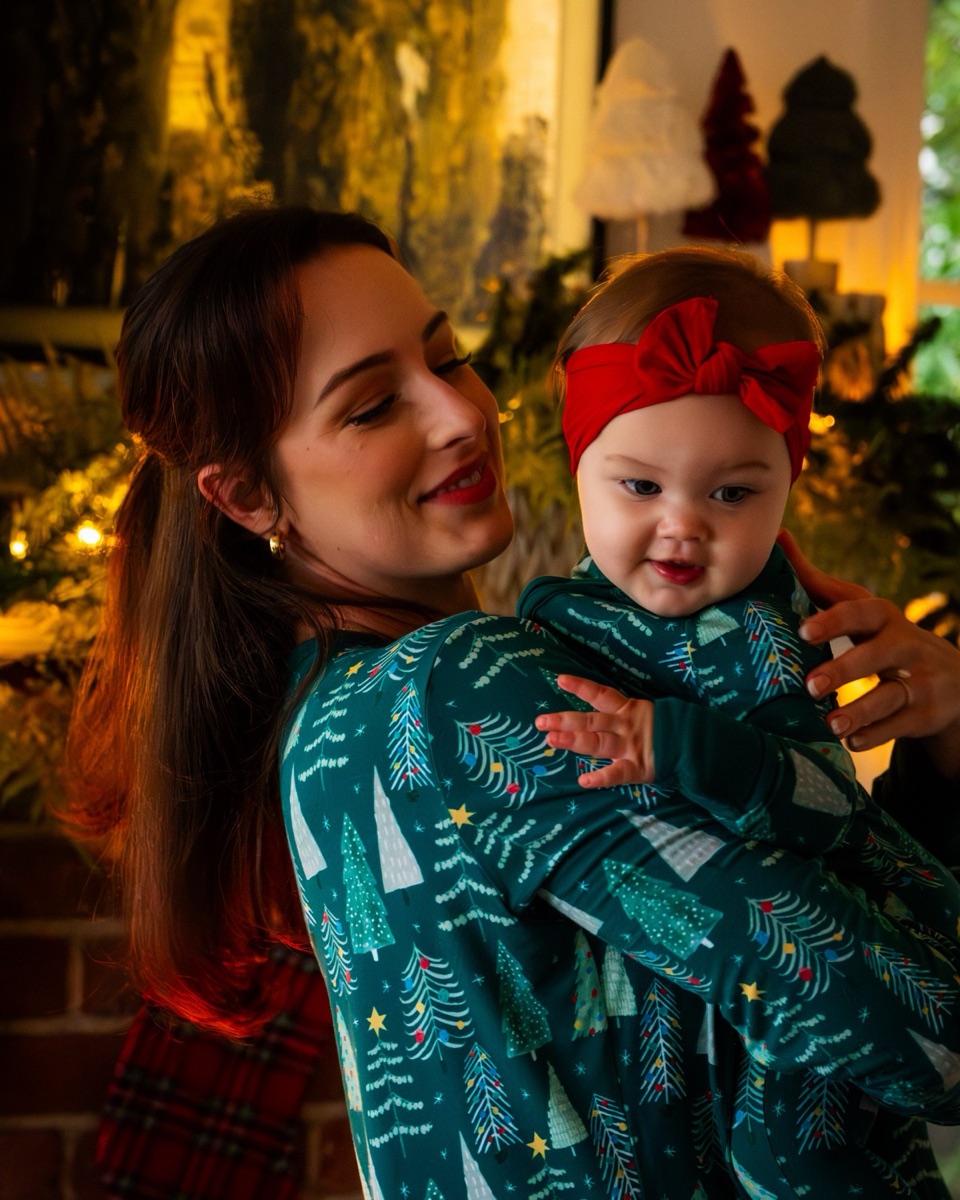 Mother holding baby against her chest in warm indoor holiday light