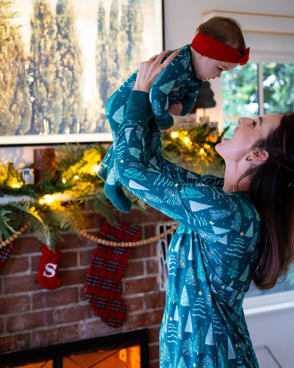 Parent lifting a laughing toddler overhead near a mantel